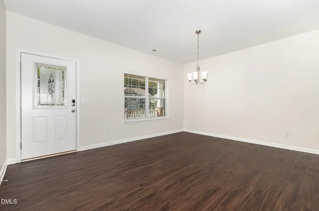 an empty room with wooden floor cabinet and windows