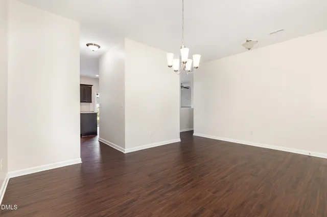 an empty room with wooden floor and stainless steel appliances