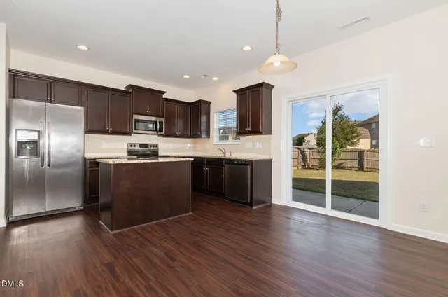 a kitchen with stainless steel appliances granite countertop a refrigerator a sink a stove and a wooden floors