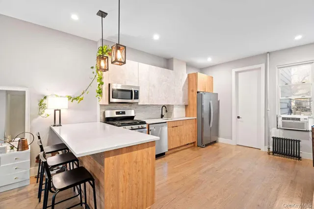 a kitchen with stainless steel appliances kitchen island granite countertop a refrigerator a stove top oven a sink dishwasher and white cabinets with wooden floor