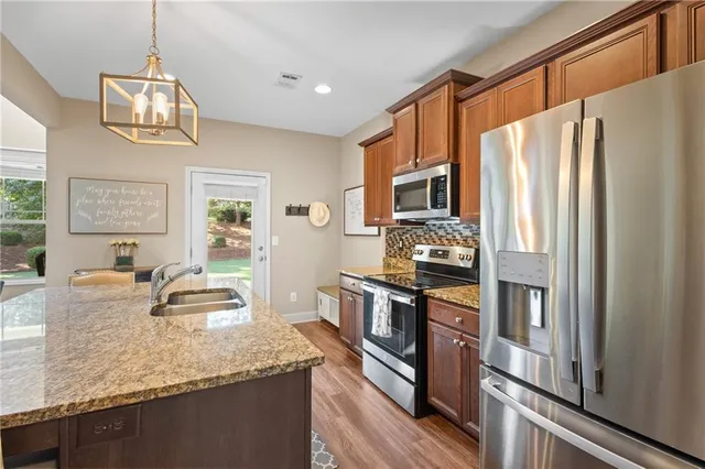 a kitchen with stainless steel appliances granite countertop a refrigerator a stove top oven a sink and dishwasher