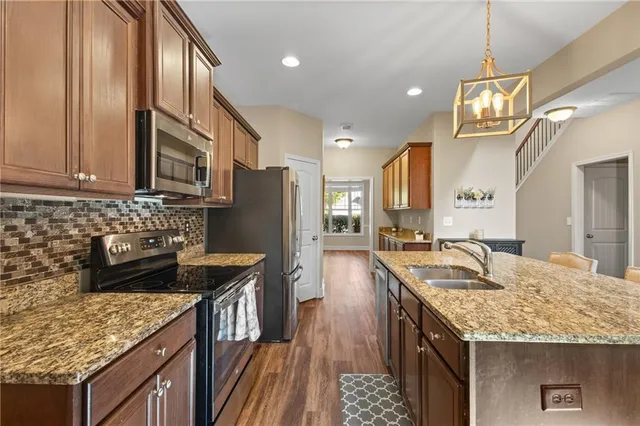 a kitchen with granite countertop kitchen island stainless steel appliances a sink stove and refrigerator