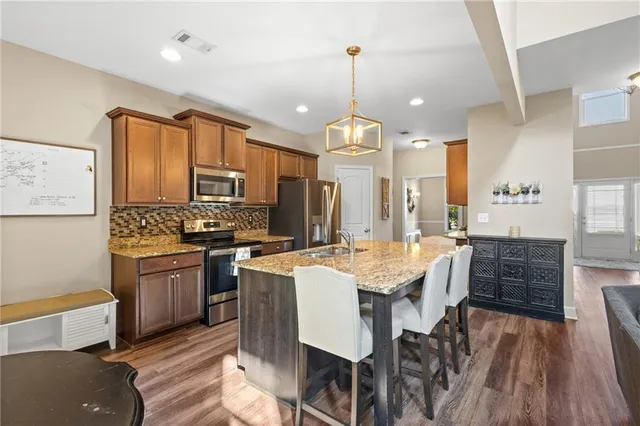 a kitchen with stainless steel appliances kitchen island granite countertop a sink stove and refrigerator
