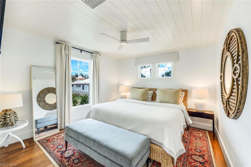 1437 Sandpiper Street Naples, FL 34102 - Photo 17 of 38 a bedroom with a bed and wooden floor