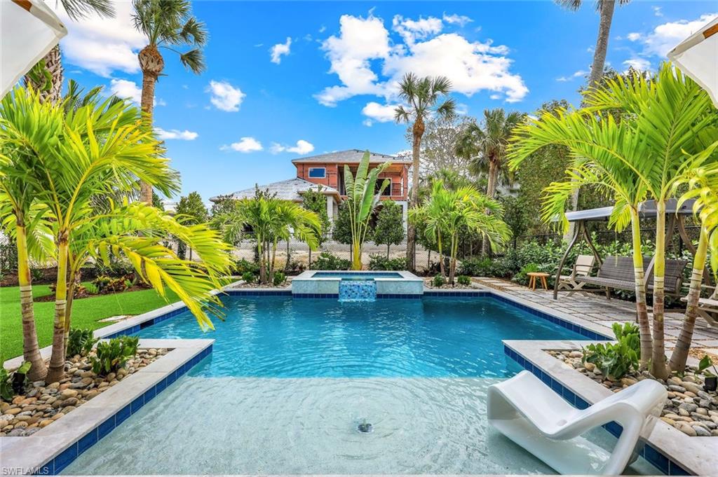 1437 Sandpiper Street Naples, FL 34102 - Photo 22 of 38 a view of a swimming pool with lounge chairs