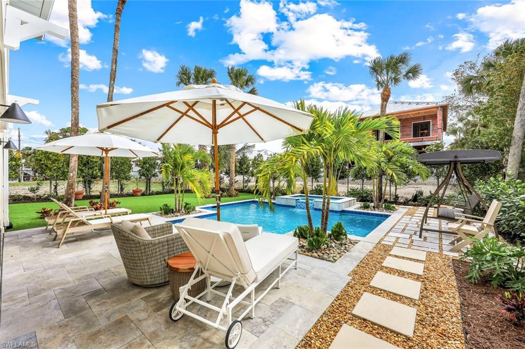 1437 Sandpiper Street Naples, FL 34102 - Photo 23 of 38 a view of a swimming pool with chairs in patio