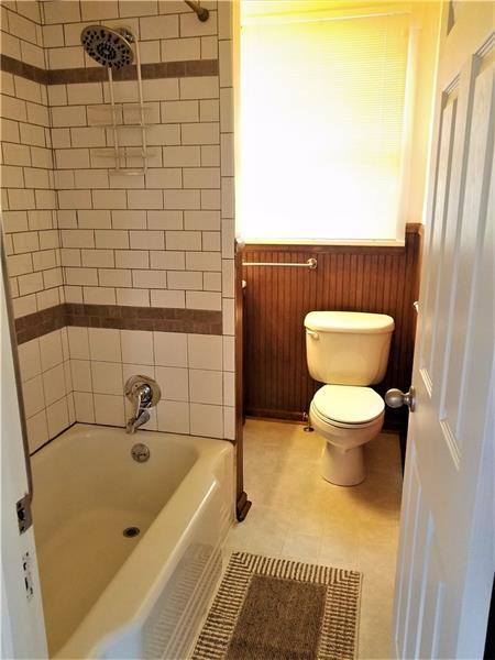 207 Reo Street Butler, PA 16001 - Photo 15 of 25 Main bathroom on the main level with ceramic tub shower and wood wains coating.