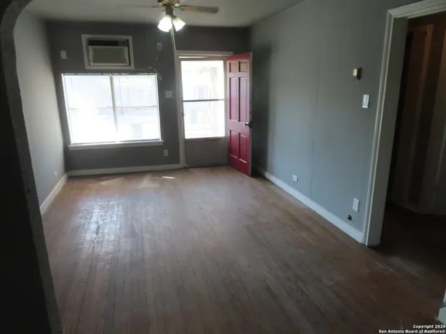 an empty room with wooden floor and windows