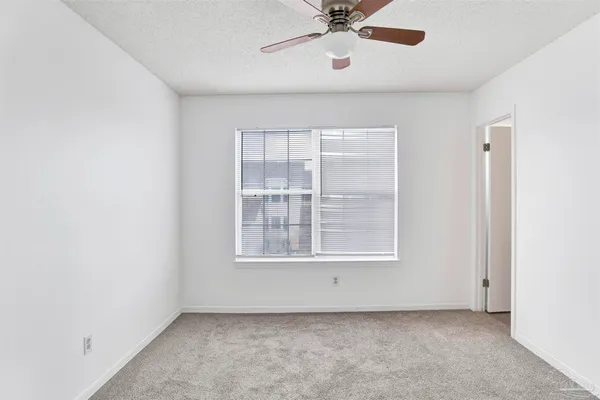 an empty room with a window and a fan