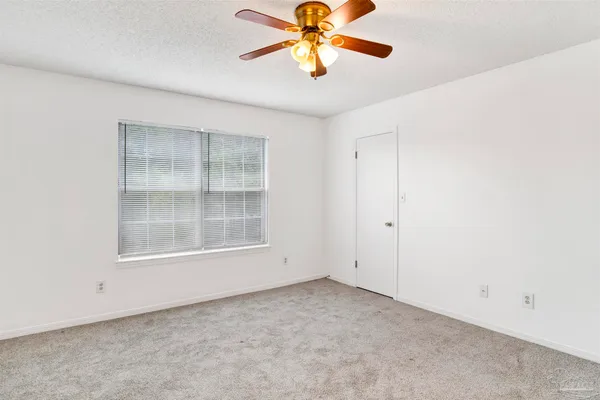 an empty room with a window and a chandelier fan