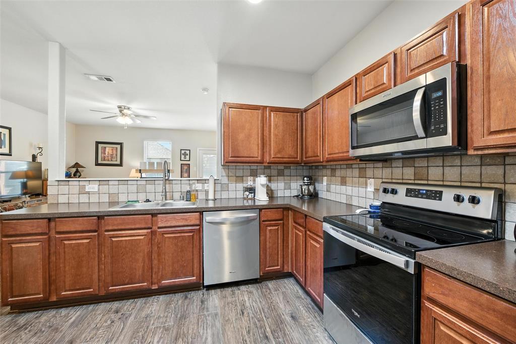 5817 Deck House Road Fort Worth, TX 76179 - Photo 17 of 28 a kitchen with stainless steel appliances granite countertop a stove a sink dishwasher and a microwave oven with wooden cabinets