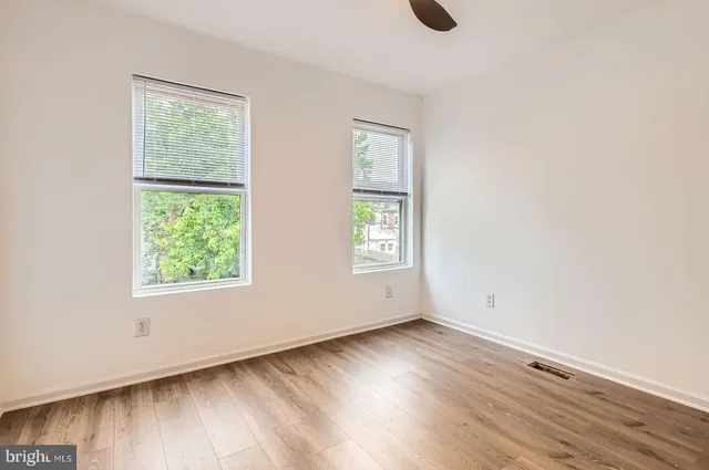an empty room with wooden floor and windows