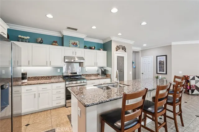 a kitchen with stainless steel appliances granite countertop a stove top oven a sink a dining table and chairs
