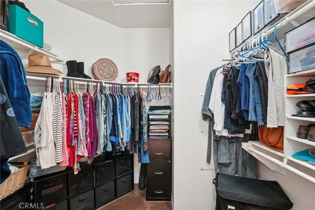 a view of walk in closet with clothes and shoes