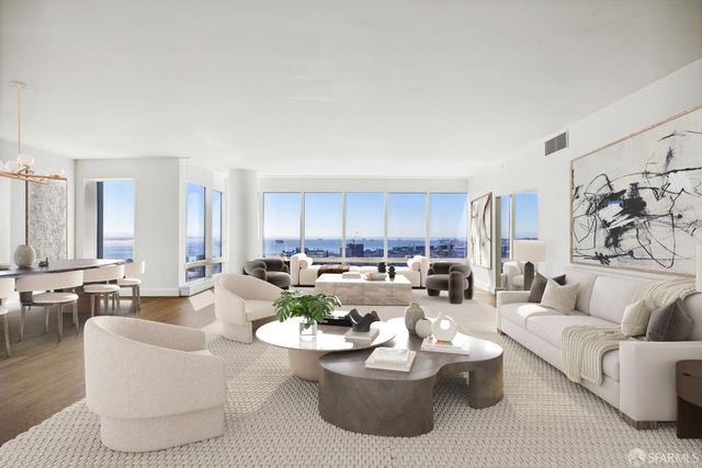 a living room with lots of white furniture and view of kitchen