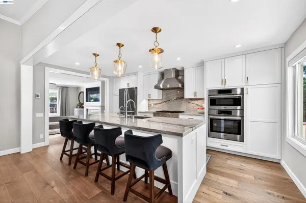 a kitchen with stainless steel appliances kitchen island granite countertop a table chairs stove and cabinets