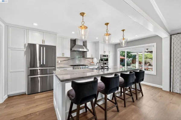 a kitchen with stainless steel appliances granite countertop a table chairs stove and refrigerator