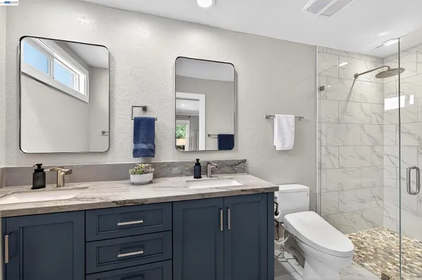 a bathroom with a double vanity sink toilet and a mirror