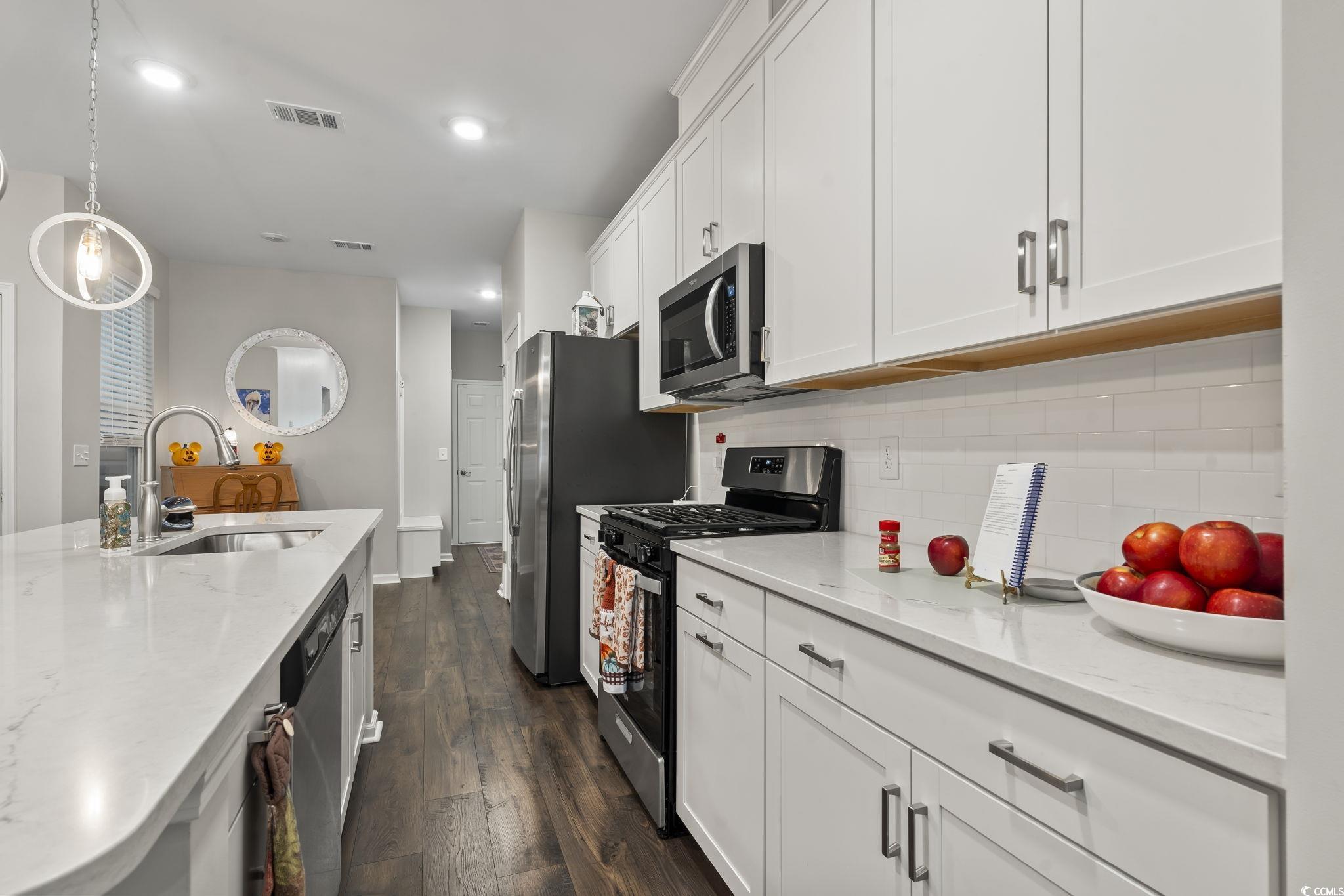 4040 Taranto Loop, Unit 5303C Myrtle Beach, SC 29579 - Photo 11 of 38 Kitchen with appliances with stainless steel finishes, light stone countertops, dark wood-style floors, white cabinetry, and recessed lighting