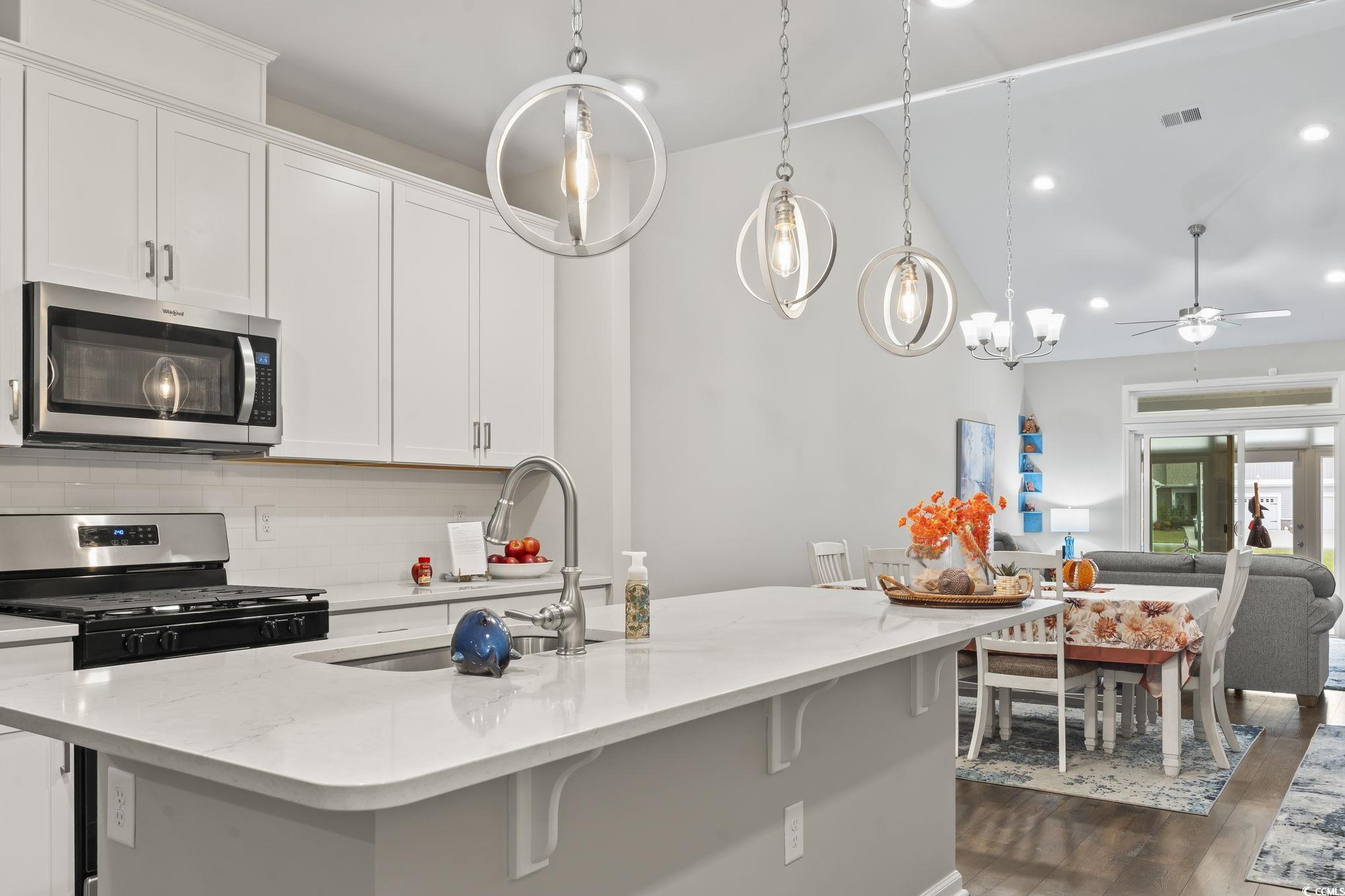 4040 Taranto Loop, Unit 5303C Myrtle Beach, SC 29579 - Photo 38 of 38 Kitchen featuring appliances with stainless steel finishes, white cabinets, decorative backsplash, open floor plan, and light stone counters