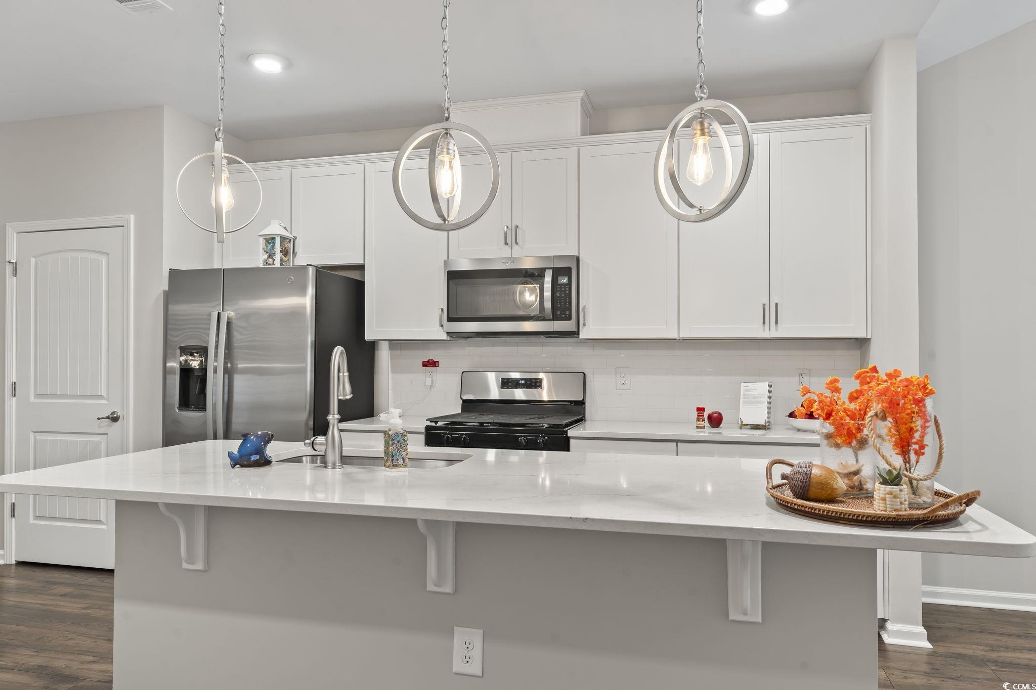 4040 Taranto Loop, Unit 5303C Myrtle Beach, SC 29579 - Photo 9 of 38 Kitchen with dark wood-type flooring, appliances with stainless steel finishes, a breakfast bar, white cabinets, and recessed lighting