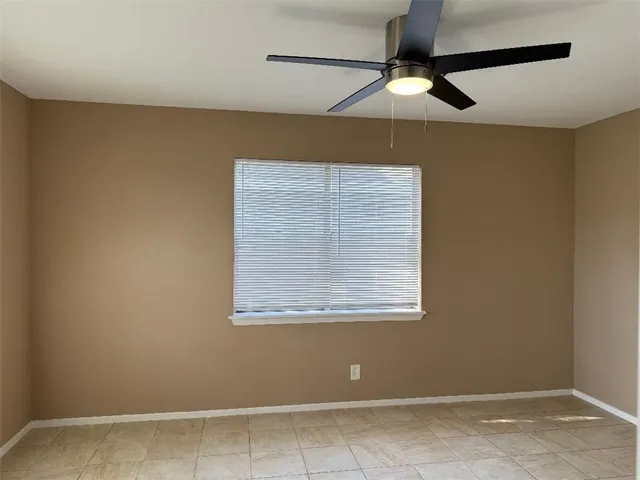 an empty room with a window and a fan