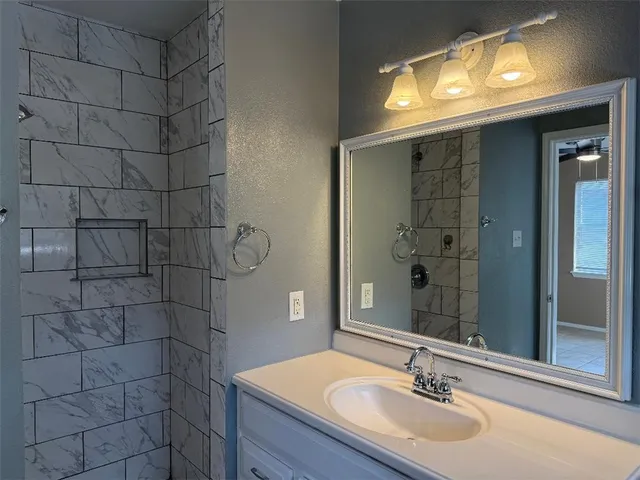 a bathroom with a sink vanity and shower