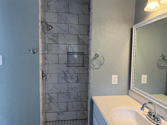 a bathroom with a granite countertop sink a mirror and shower