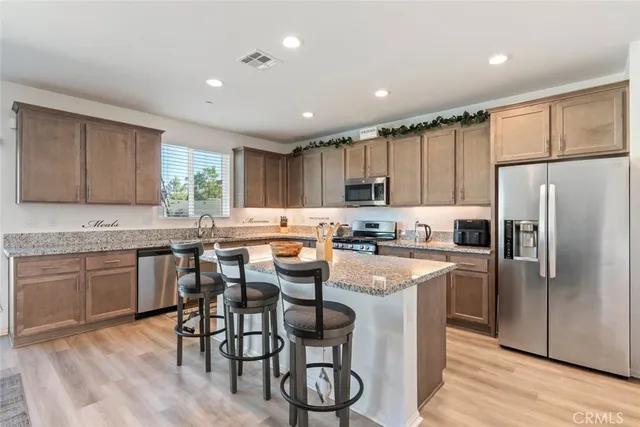 a kitchen with stainless steel appliances granite countertop a table chairs refrigerator sink and cabinets