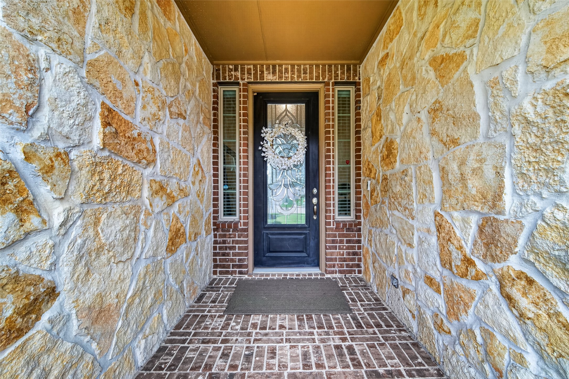 25611 Ellis Ridge Court Katy, TX 77494 - Photo 4 of 49 This inviting entryway features a charming stone and brick design, leading to a decorative glass front door, perfect for a warm welcome.