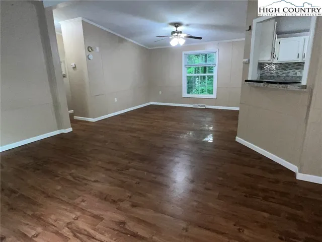 an empty room with wooden floor cabinet and windows