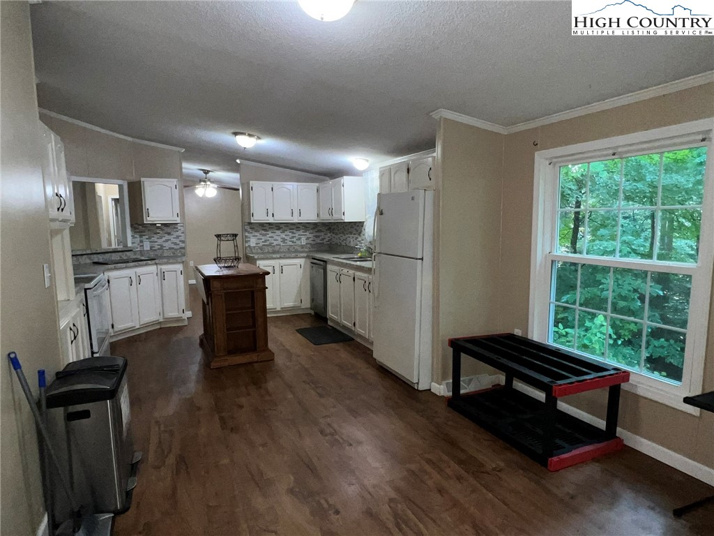 1980 Mountaindale Road Vilas, NC 28692 - Photo 7 of 25 a open kitchen with granite countertop a stove a sink dishwasher a dining table and chairs with wooden floor