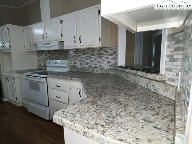 a kitchen with granite countertop a stove sink and cabinets