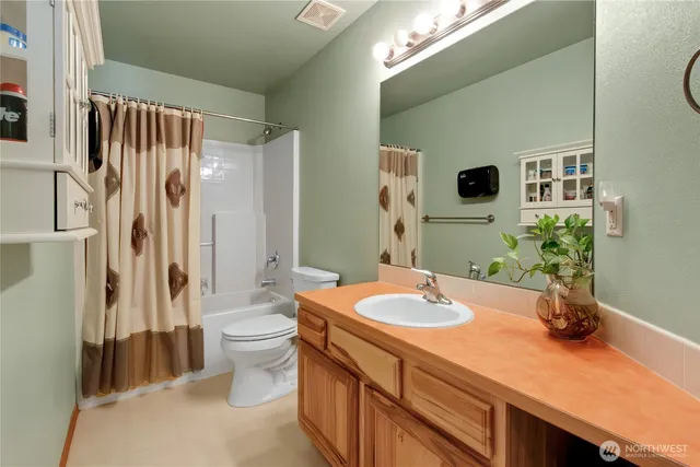 a bathroom with a granite countertop sink a toilet a mirror and shower