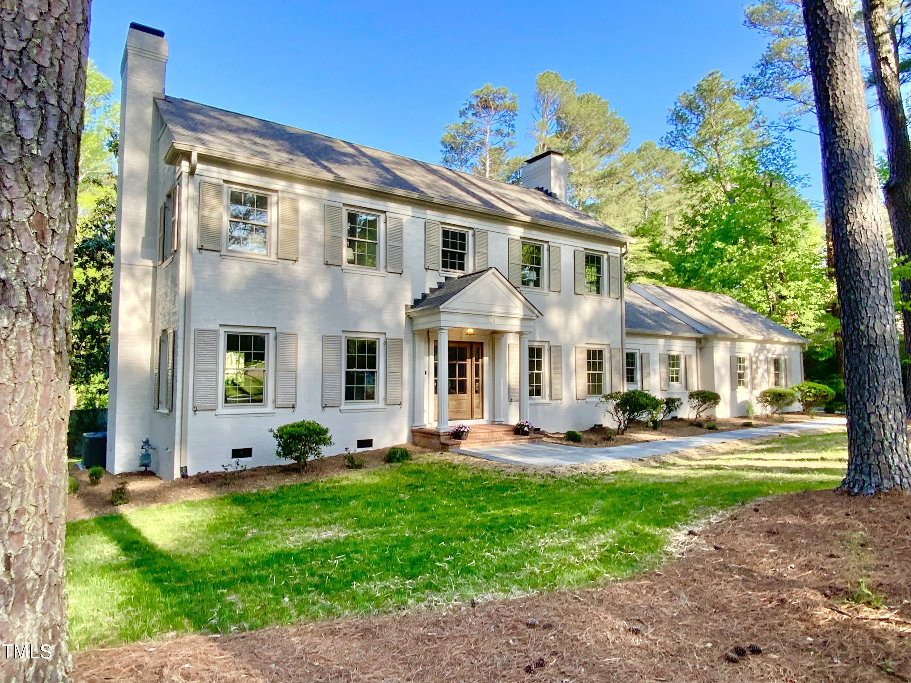 a front view of a house with garden and trees
