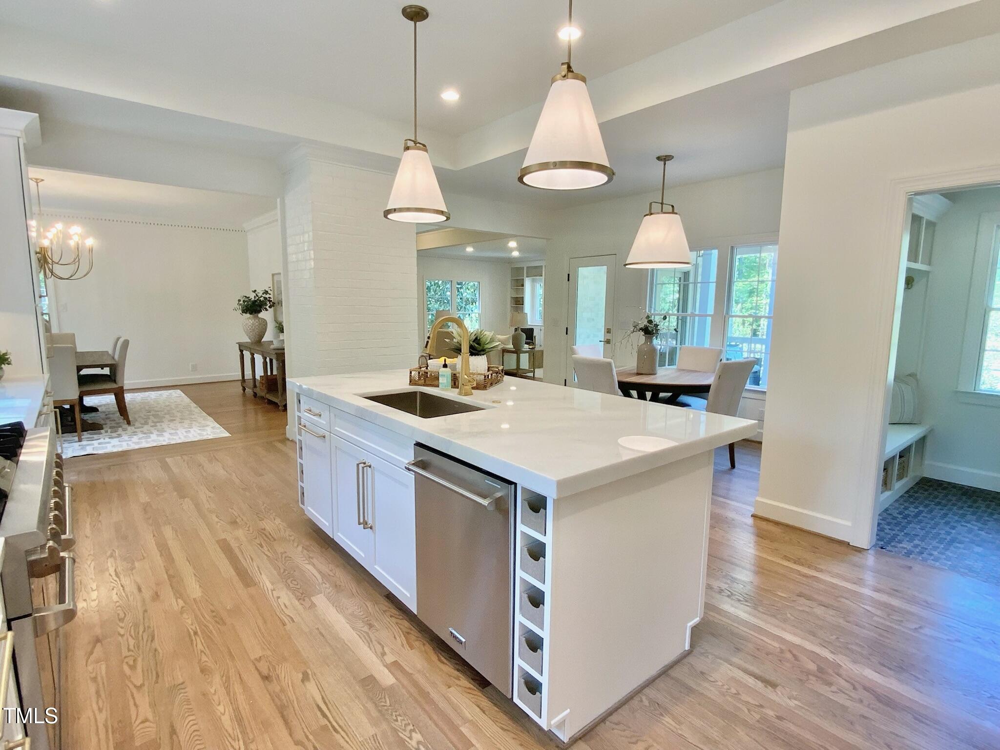 3838 Regent Road Durham, NC 27707 - Photo 19 of 55 a large kitchen with stainless steel appliances a large counter top a sink a stove and a wooden floors
