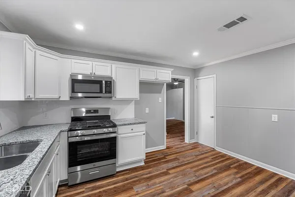 a kitchen with granite countertop a stove top oven and cabinets