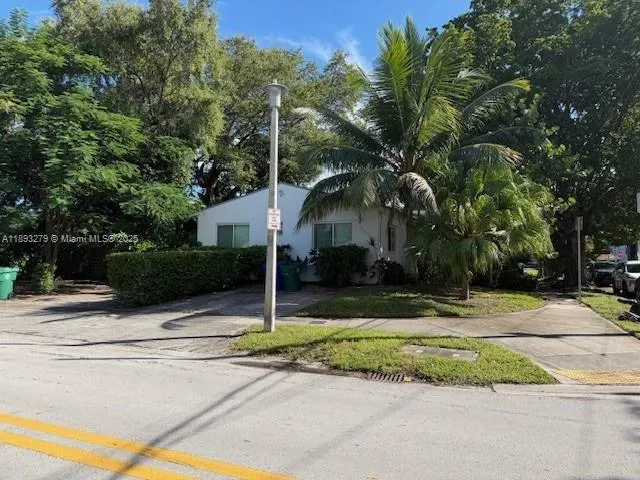 a view of a house with small yard plants and palm trees