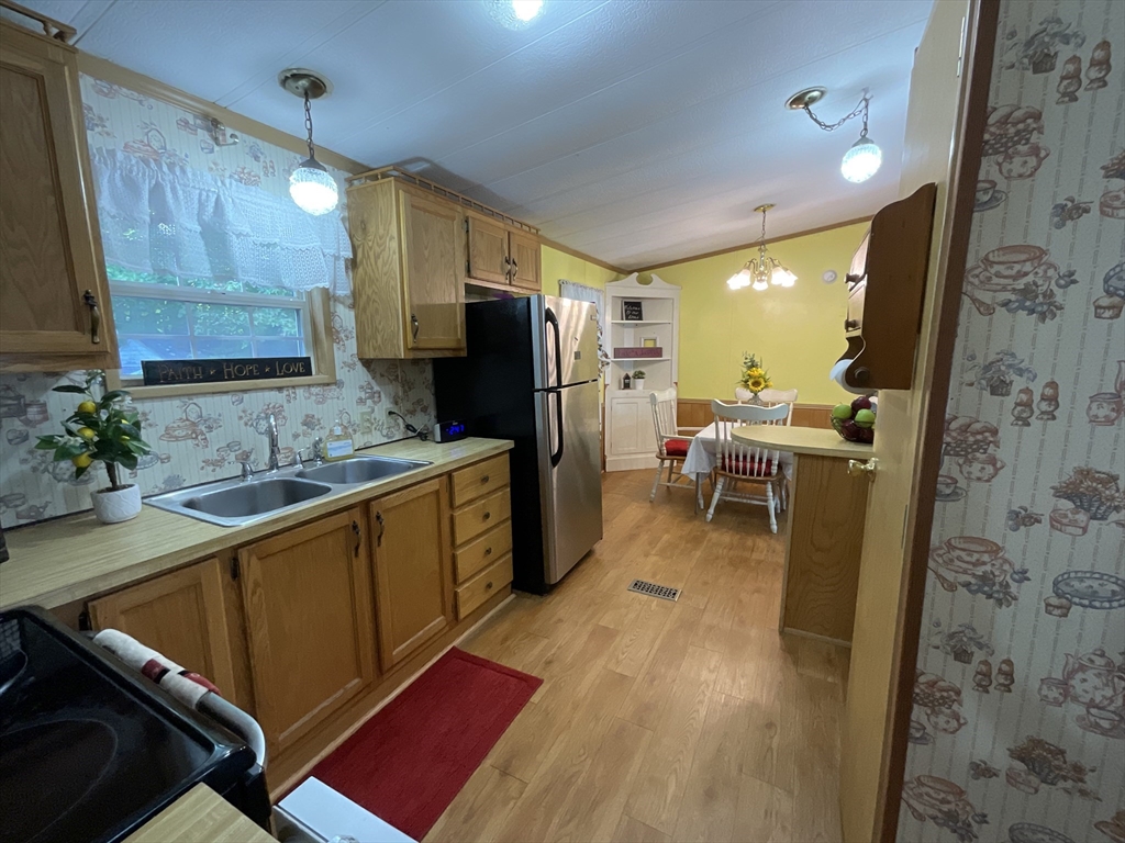 16 Agent Road Raymond, NH 03077 - Photo 15 of 35 a kitchen with stainless steel appliances granite countertop a refrigerator a sink dishwasher and wooden cabinets with a large window