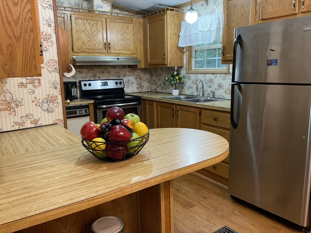 16 Agent Road Raymond, NH 03077 - Photo 29 of 35 a kitchen with stainless steel appliances a sink a refrigerator a stove and wooden cabinets