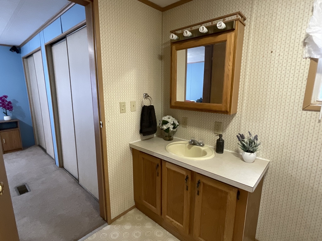 16 Agent Road Raymond, NH 03077 - Photo 30 of 35 a bathroom with a sink a mirror and a window