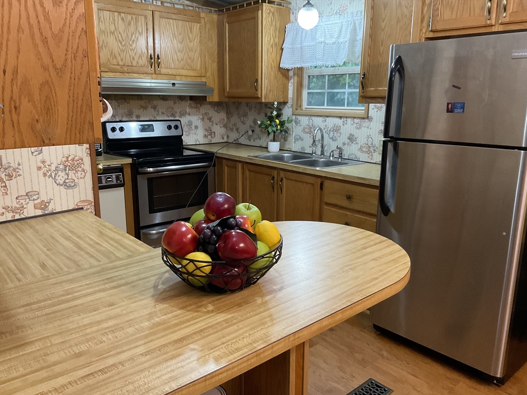16 Agent Road Raymond, NH 03077 - Photo 35 of 35 a kitchen with stainless steel appliances a stove a refrigerator and cabinets