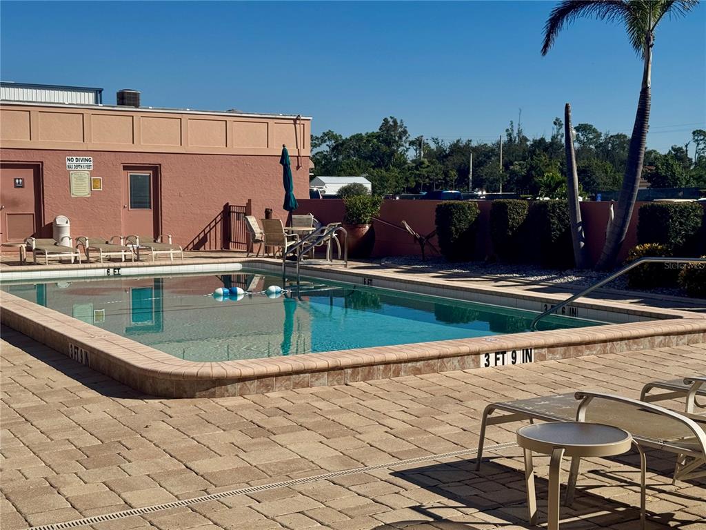 3170 Matecumbe Key Road, Unit 115 Punta Gorda, FL 33955 - Photo 30 of 43 a view of a swimming pool with a chair and tables