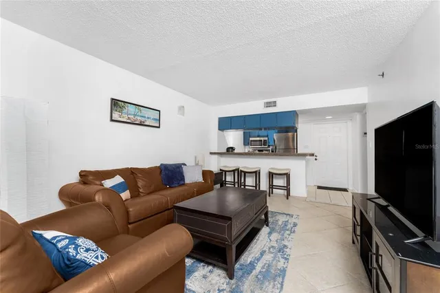 a living room with furniture a flat screen tv and kitchen view