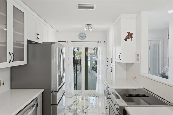 a kitchen with stainless steel appliances a refrigerator a sink and white cabinets