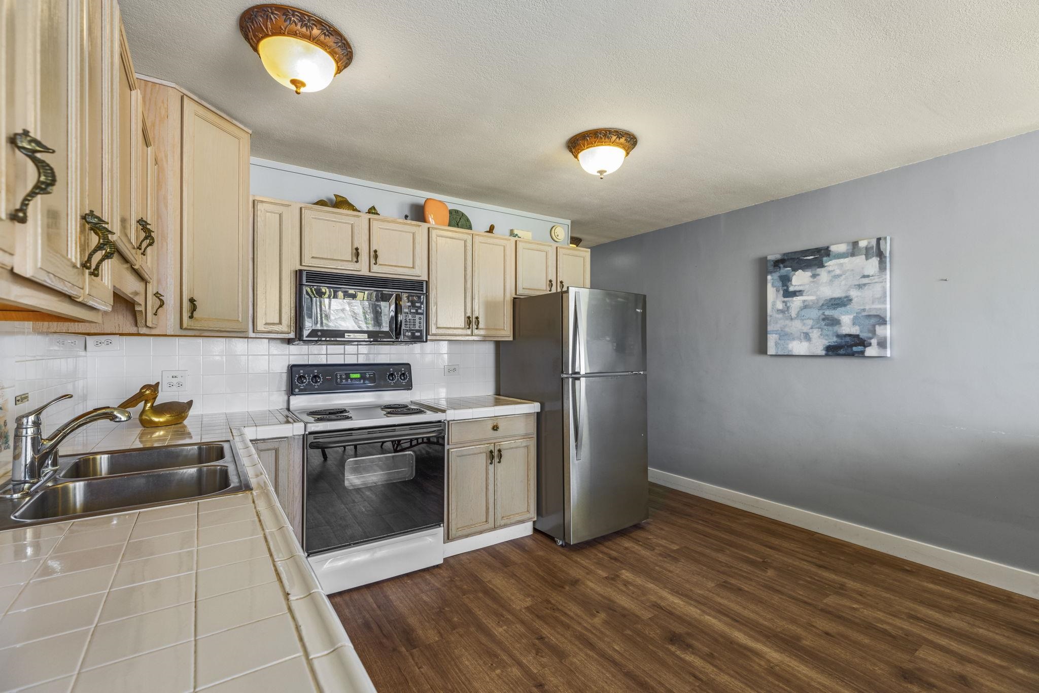 1310 Uluniu Road, Unit 317 Kihei, HI 96753 - Photo 21 of 50 a kitchen with stainless steel appliances granite countertop a refrigerator and a stove top oven