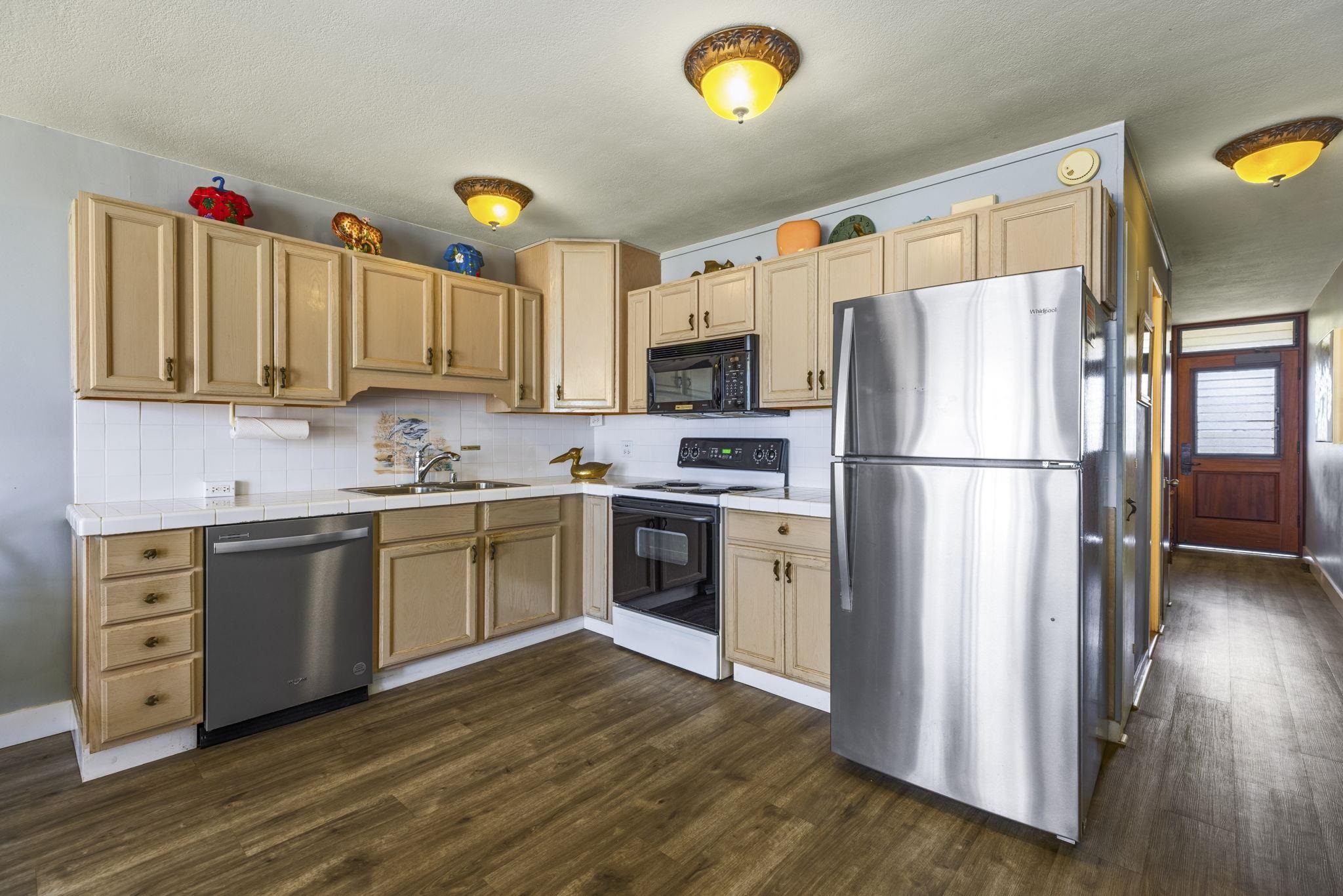 1310 Uluniu Road, Unit 317 Kihei, HI 96753 - Photo 23 of 50 a kitchen with granite countertop a refrigerator stove and wooden floor