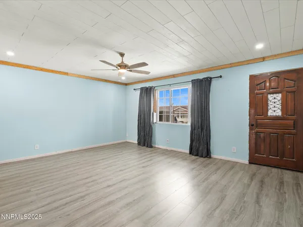 a view of an empty room with window and wooden floor