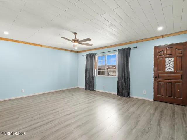 a view of an empty room with window and wooden floor