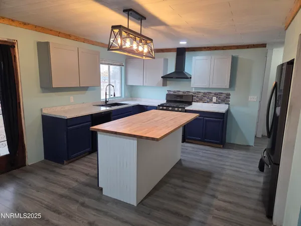 a kitchen with stainless steel appliances granite countertop a stove a refrigerator a sink dishwasher and wooden cabinets with wooden floor